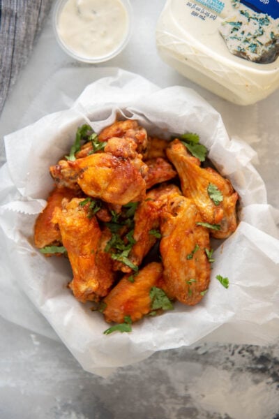 buffalo chicken wings in round bowl wrapped in paper