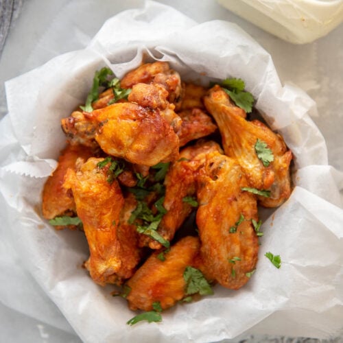 buffalo chicken wings in round bowl wrapped in paper