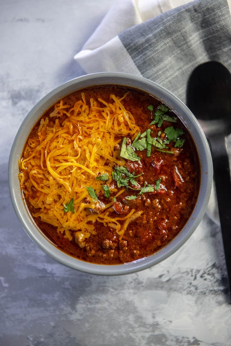 gray bowl filled with beef chili topped with melted cheese