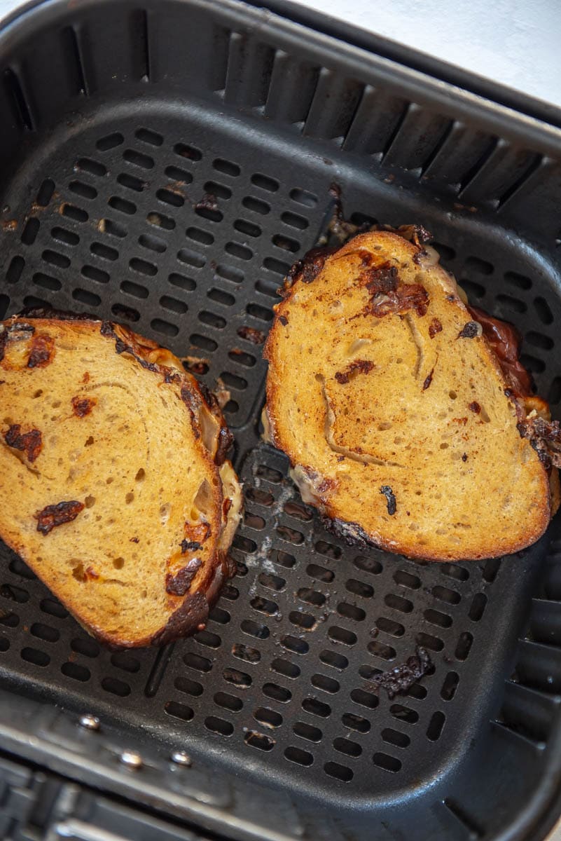 2 cooked sourdough grilled cheese sandwiches in air fryer basket