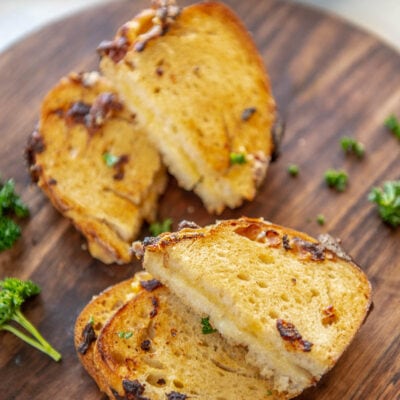 sourdough grilled cheese sandwich halves arranged on wood platter with parsley garnish