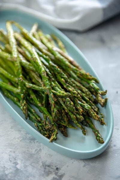 cooked asparagus in a white serving dish