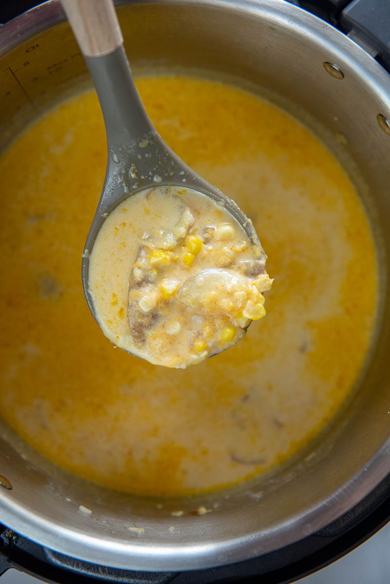 ladle full of corn chowder with potatoes hovering over instant pot