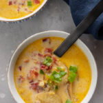 two blue and white bowls filled with corn chowder topped with crumbled bacon and green onions