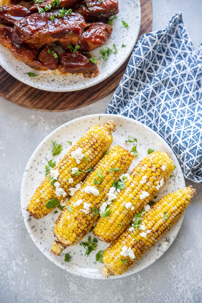 corn on the cob on a plate with barbeque ribs