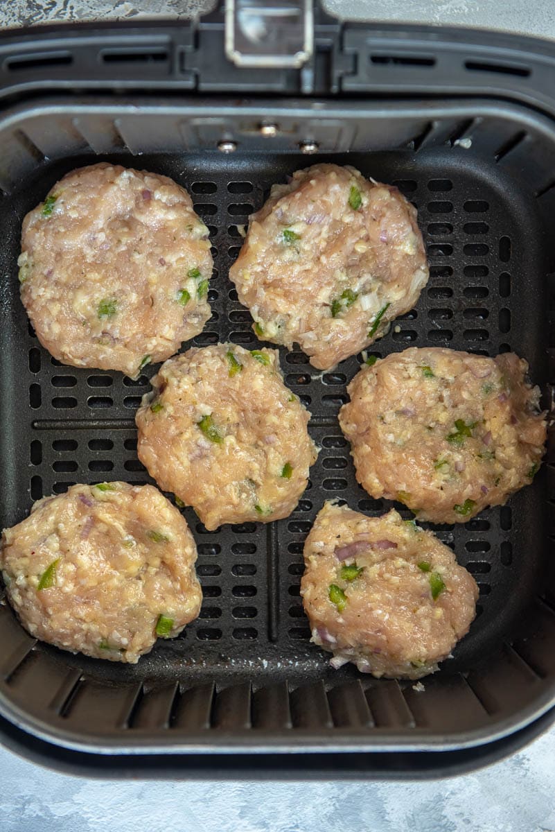 chicken sausage patties in air fryer basket ready to cook