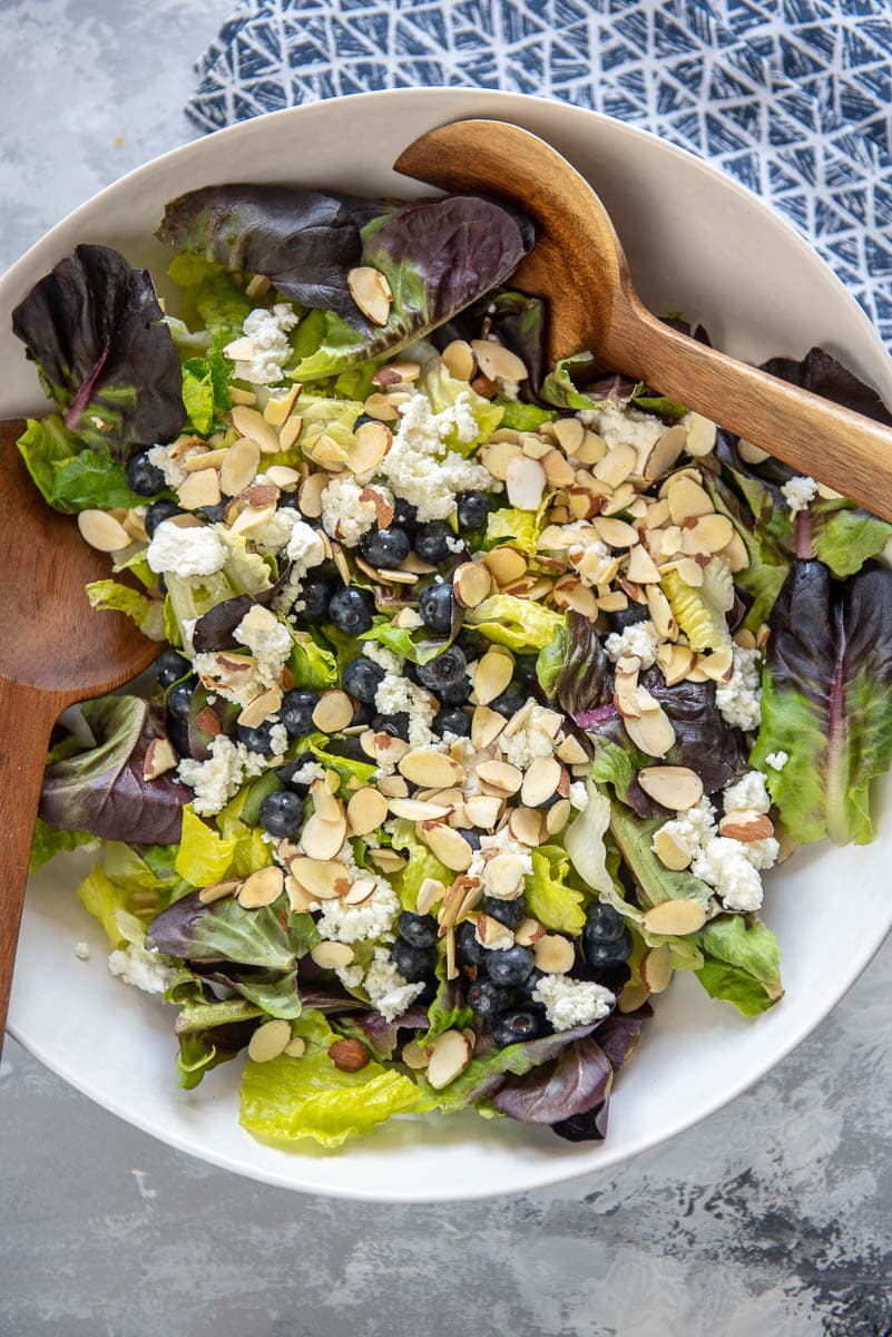 blueberry salad with sliced almonds and goat cheese in white bowl