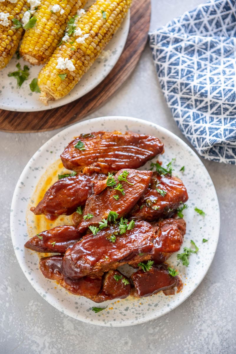 white plate with instant pot ribs and another plate in corner with corn on the cob