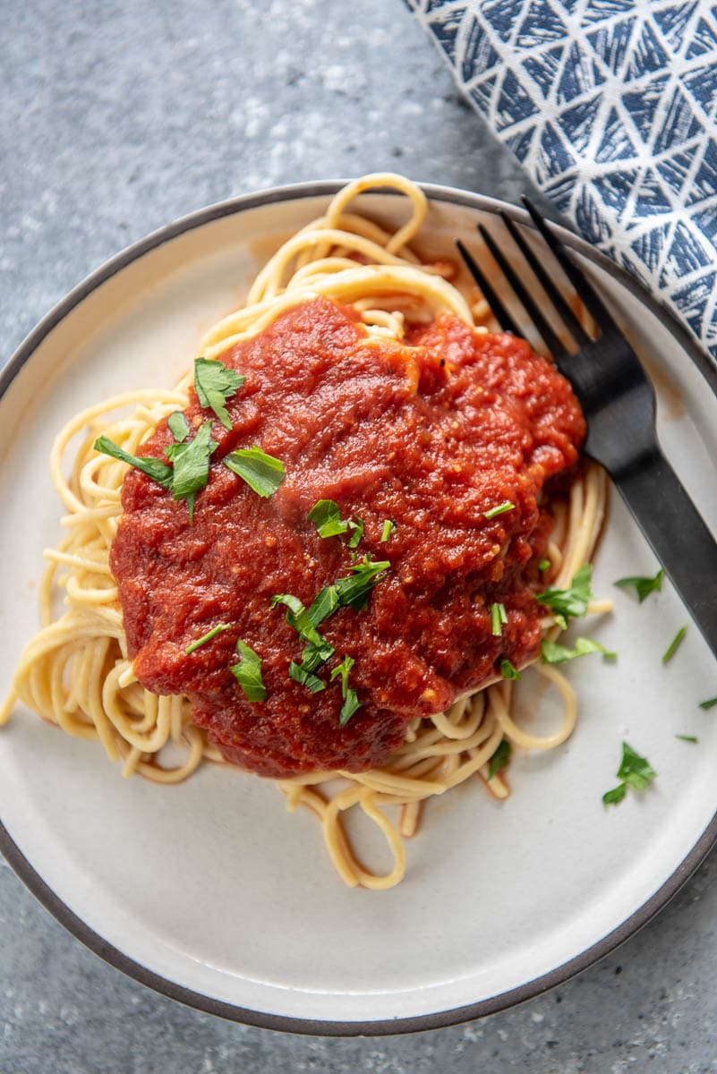 spaghetti and sauce on white plate with fork