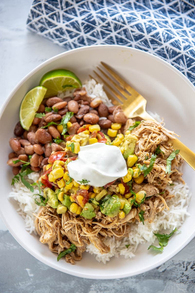 burrito bowl in a white bowl with lime and sour cream
