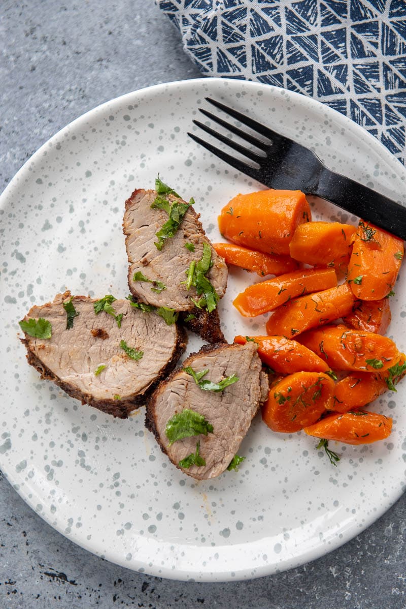 pork tenderloin and carrots on white plate with fork