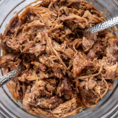 carnitas in a bowl with two spoons