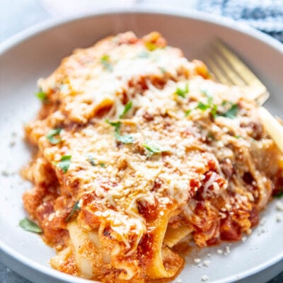 piece of cheese lasagna in a shallow white bowl topped with parmesan