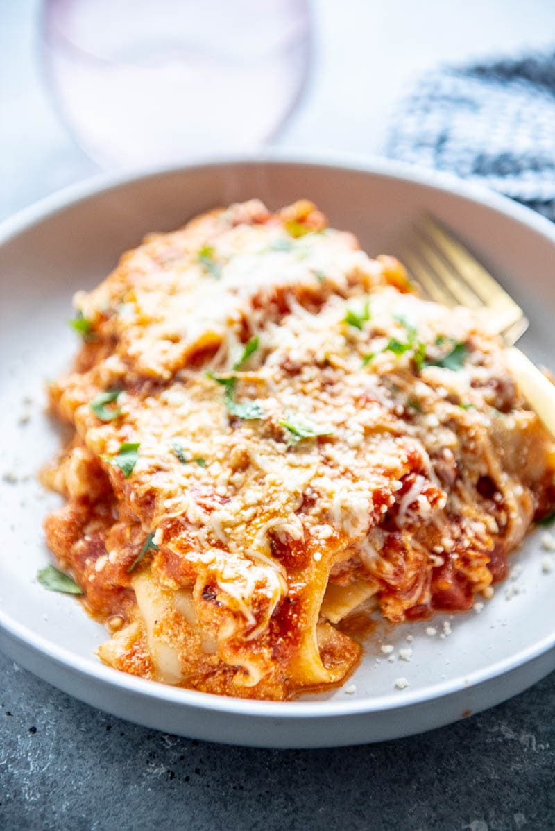 piece of cheese lasagna in a shallow white bowl topped with parmesan