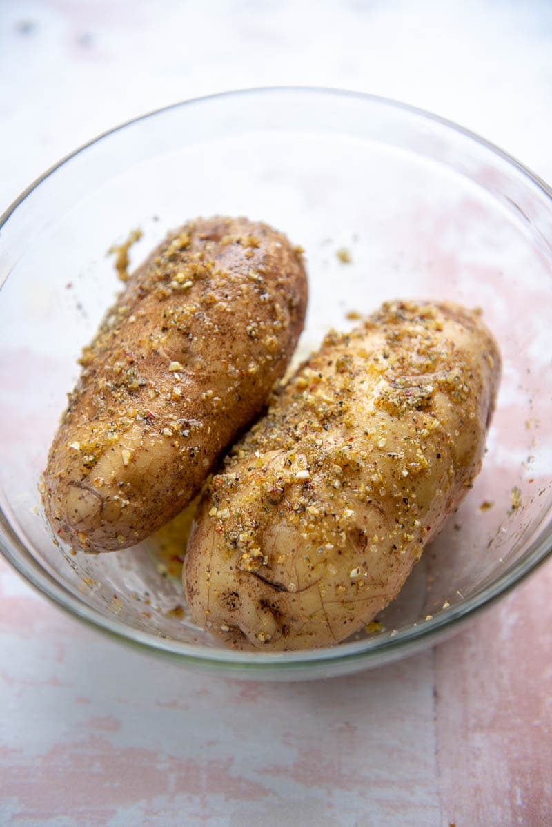 two potatoes in a glass bowl with seasoning