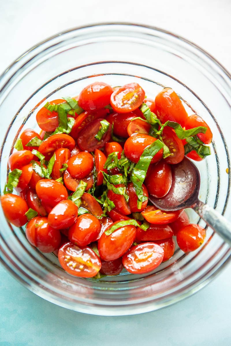 balsamic tomato salad in a glass bowl with spoon