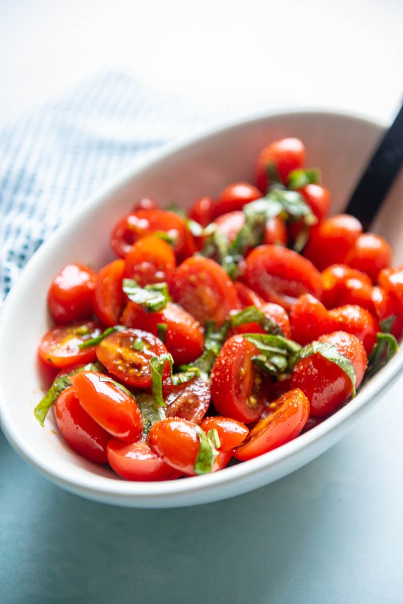 closeup of balsamic tomato salad in a white bowl with spoon