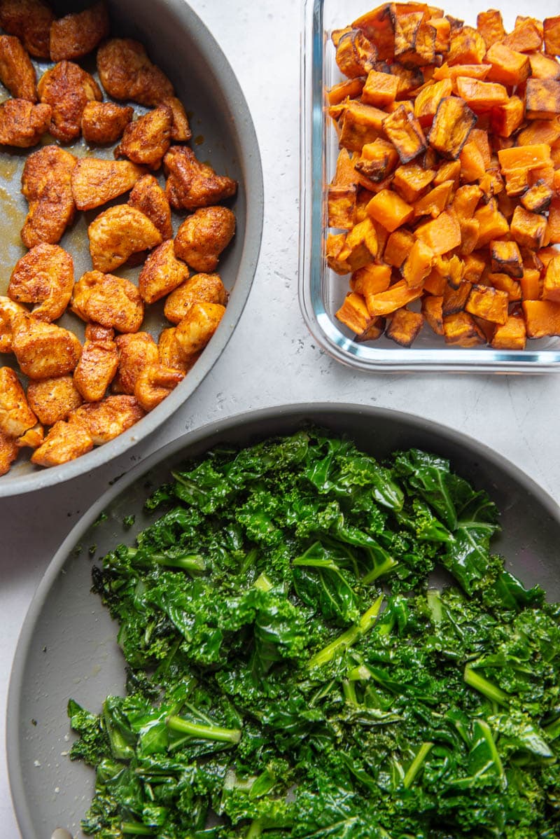 cajun chicken bites, sweet potatoes, and kale in bowls