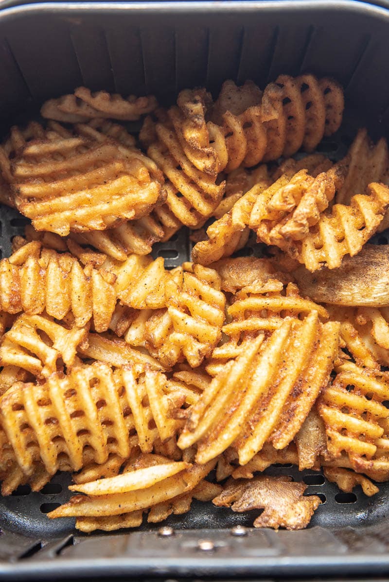 cooked waffle fries in an air fryer basket