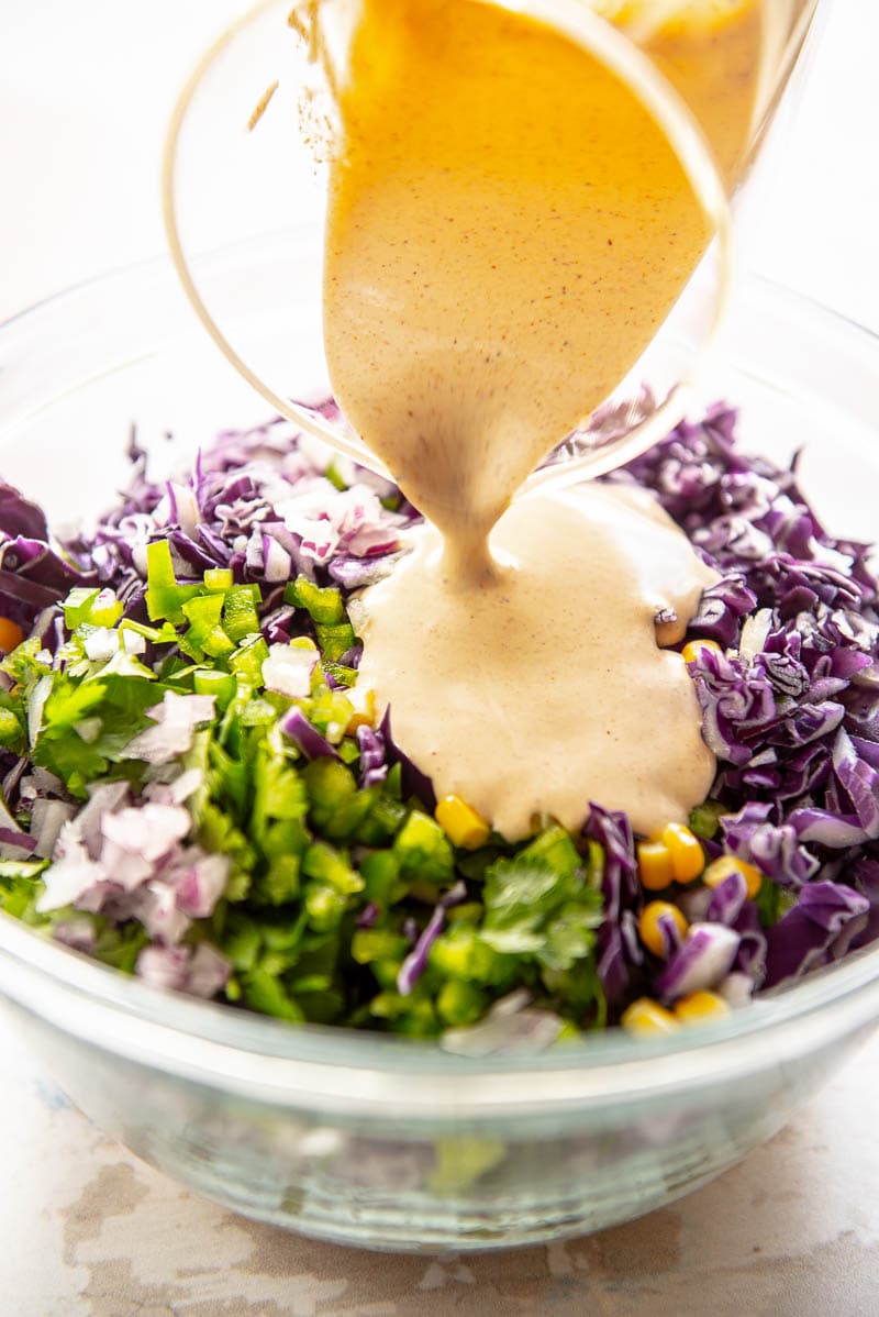 dressing poured over ingredients for corn slaw