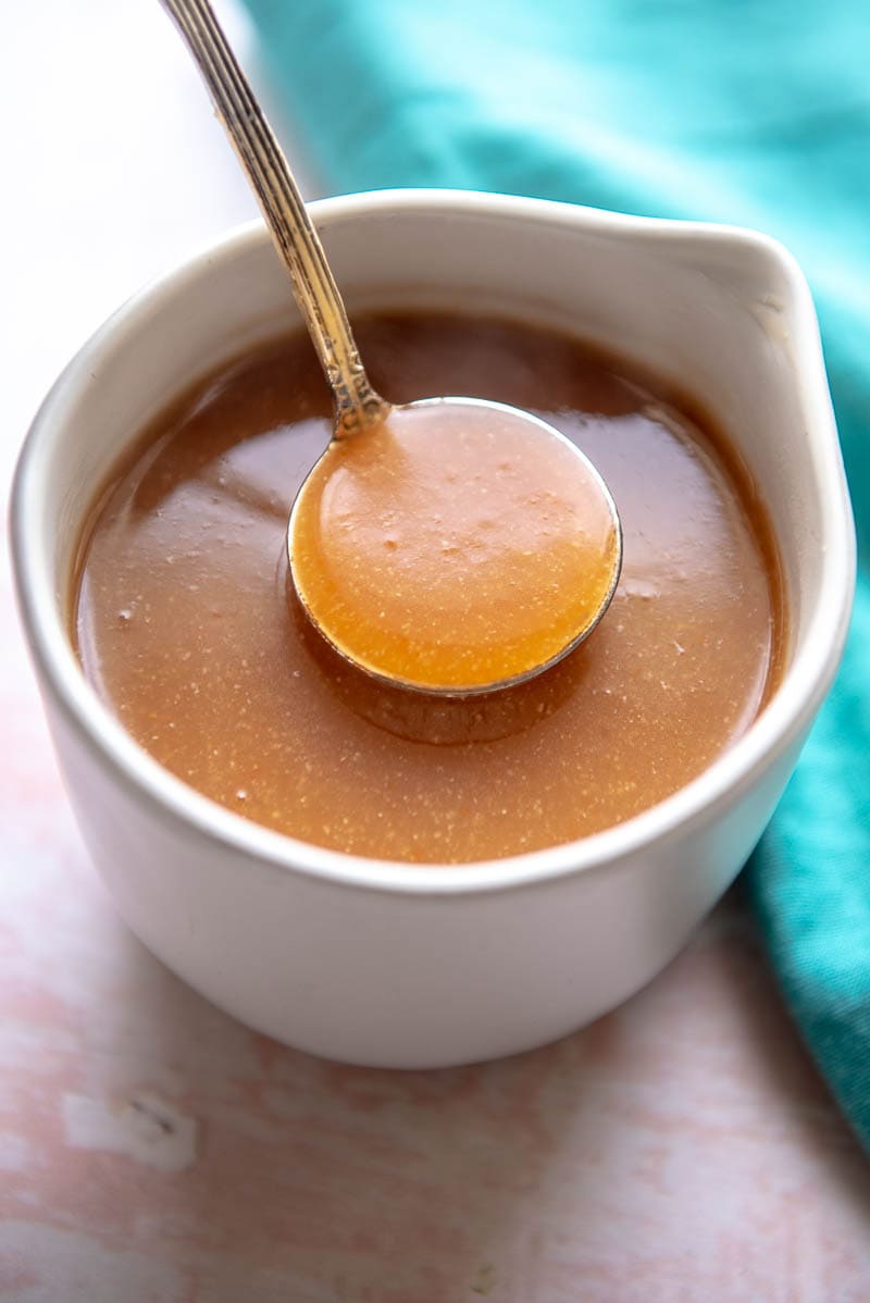 white gravy bowl filled with brown gravy and a ladle 