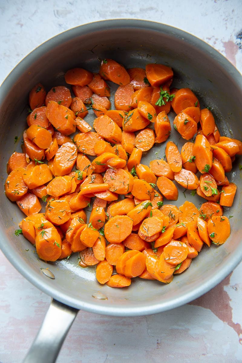 skillet with cooked carrots topped with fresh chopped herbs