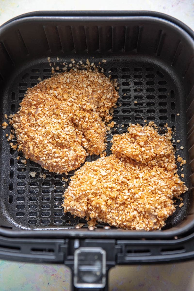 breaded chicken breasts ready to cook in air fryer basket