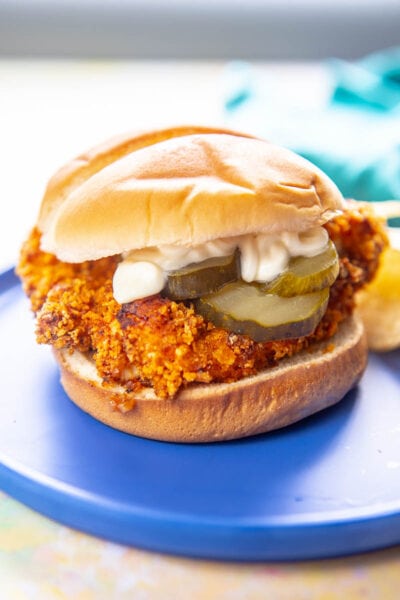 breaded chicken sandwich with pickles and mayo on a blue plate