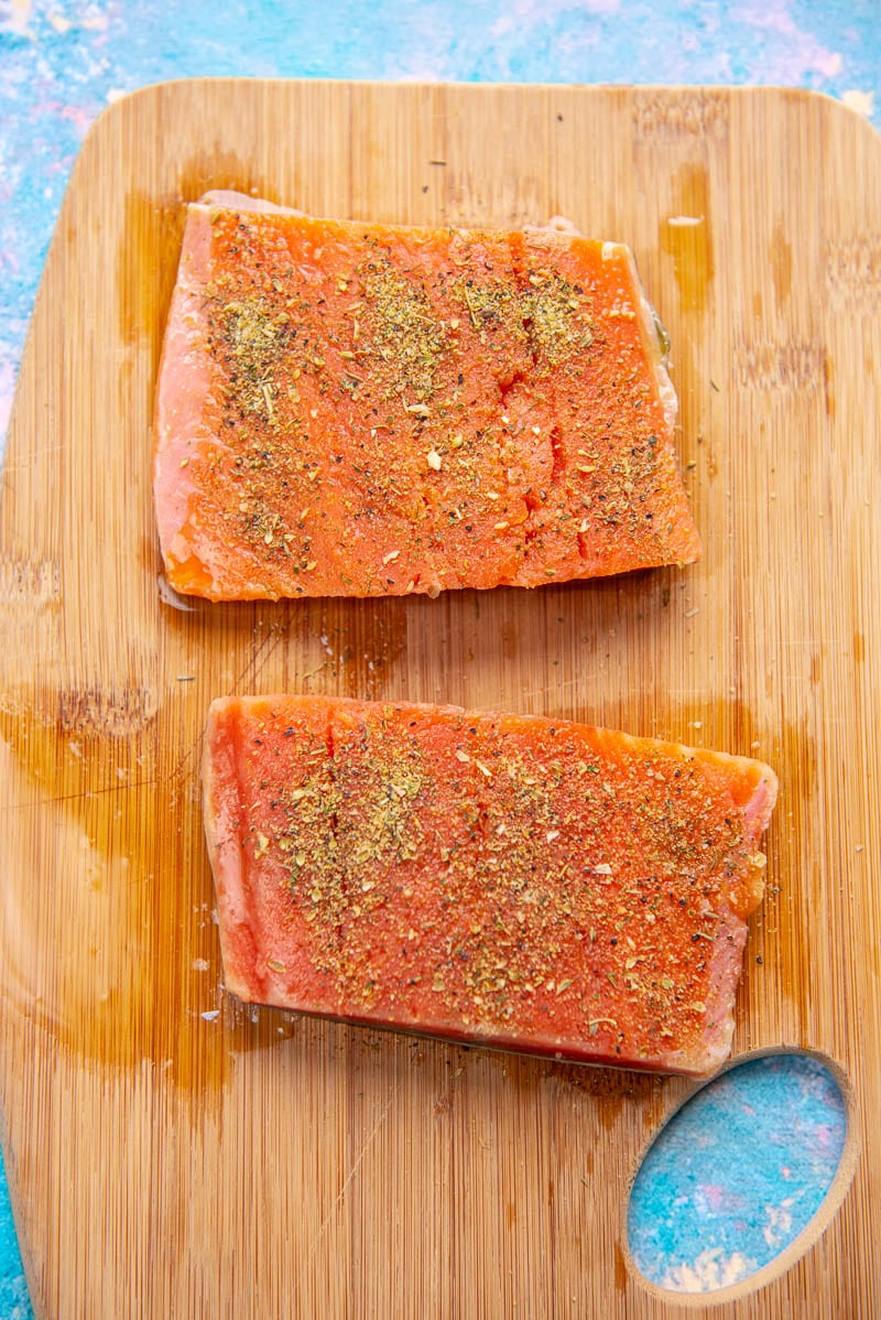 2 pieces of seasoned raw salmon on cutting board