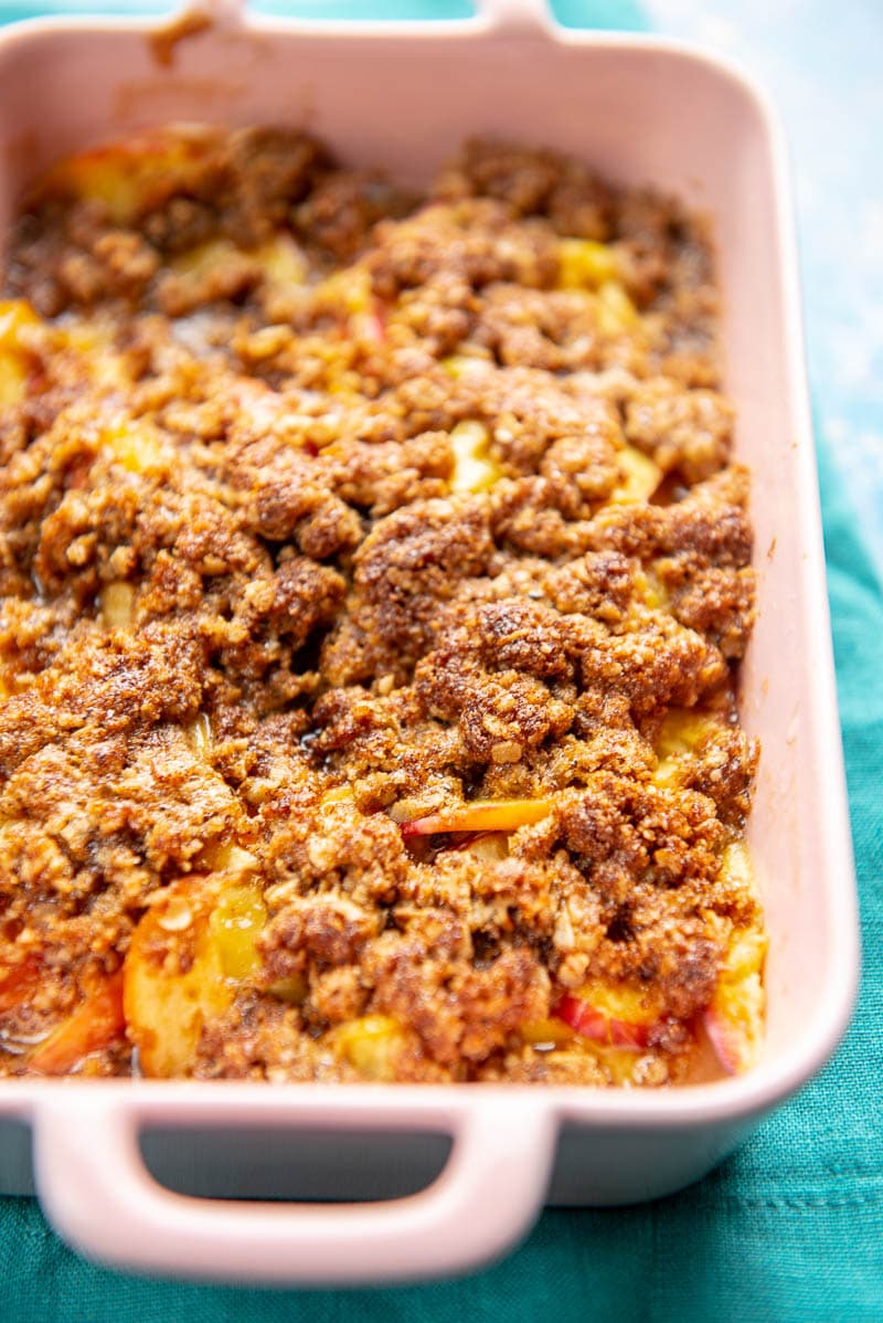small pink casserole dish with peach cobbler