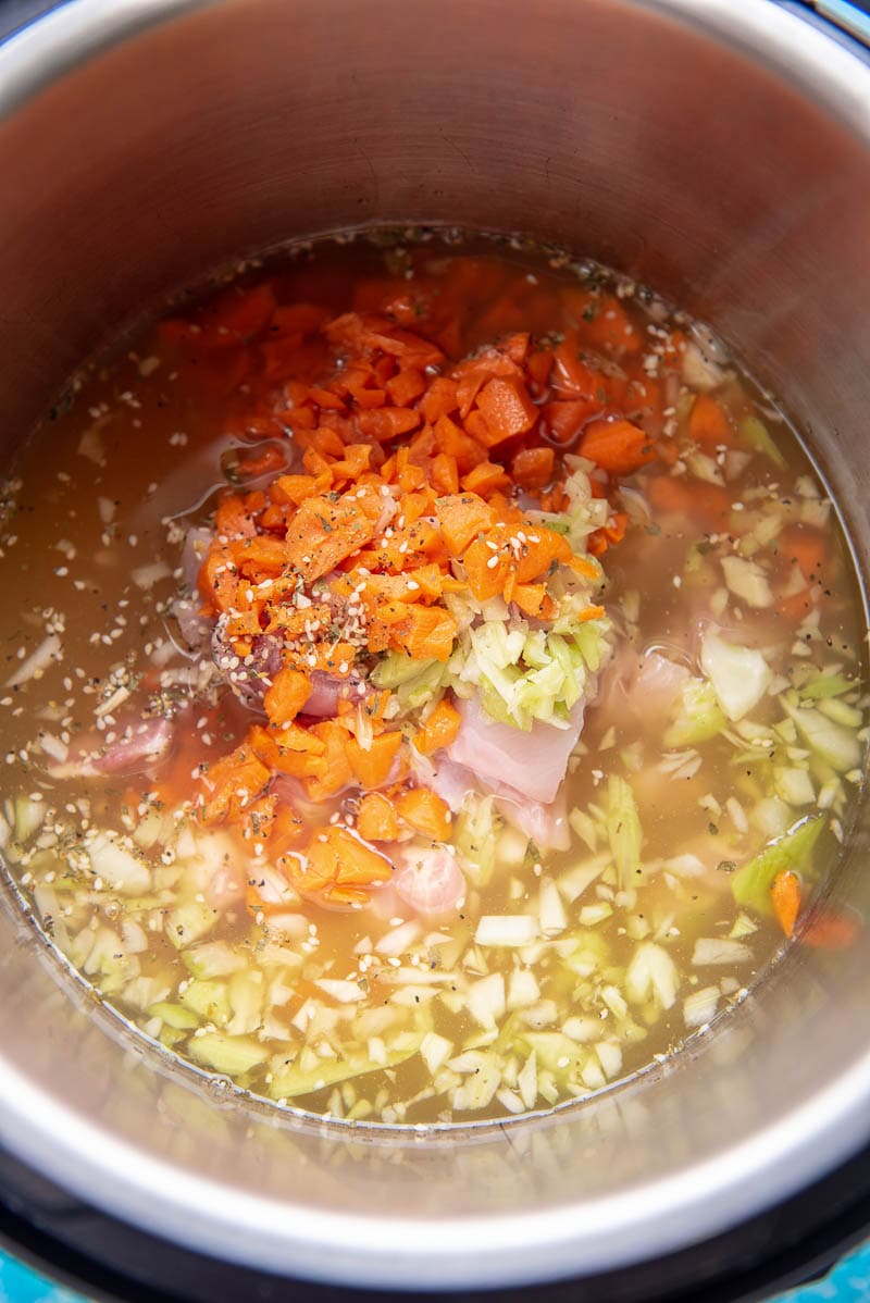instant pot liner filled with chicken, carrots and broth