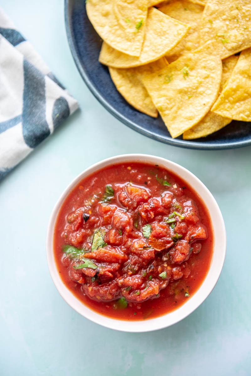 pink bowl with red salsa and blue bowl with corn chips
