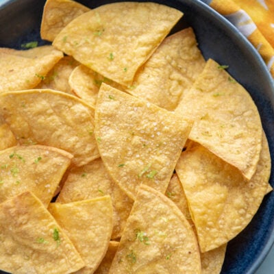 close up of tortilla chips on a blue plate topped with lime zest