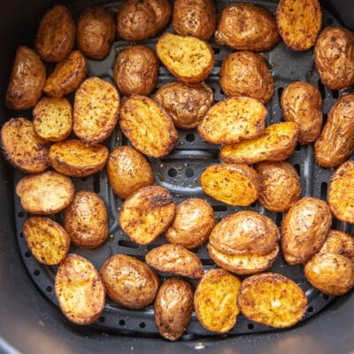 air fryer basket with roasted seasoned red poatoes