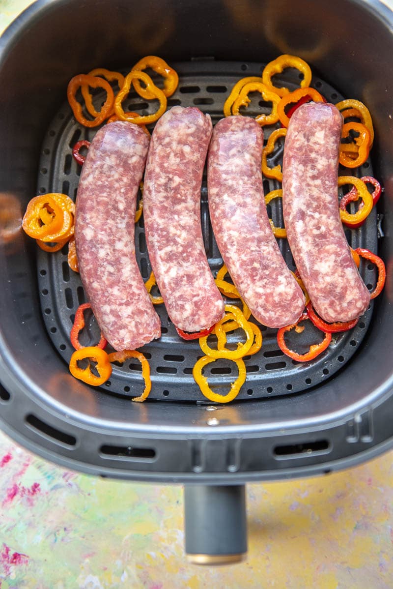 raw sausage and mini peppers in air fryer basket