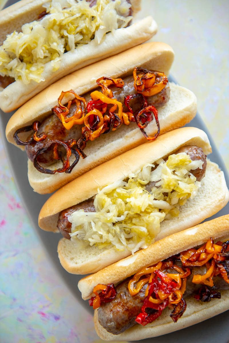 4 brats in buns topped alternating with peppers or sauerkraut 