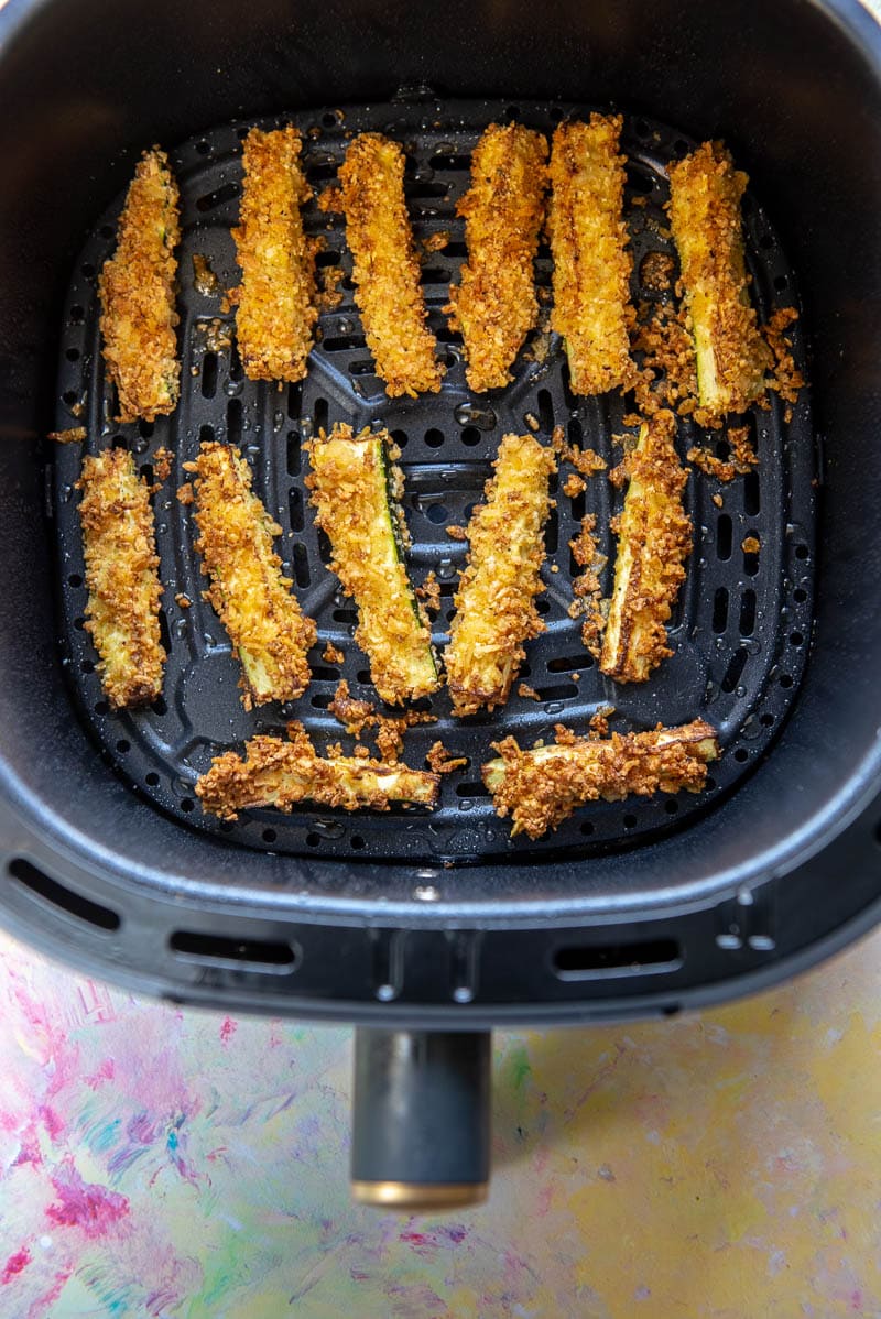 zucchini fries lined up in air fryer basket ready to eat