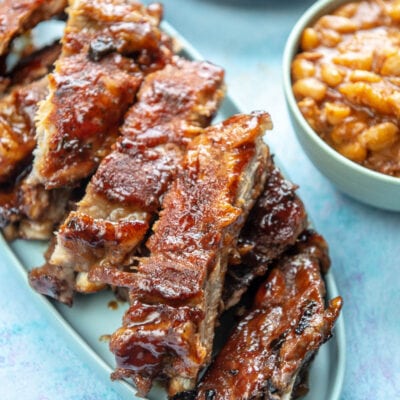 platter of ribs next to beans and corn on the cob