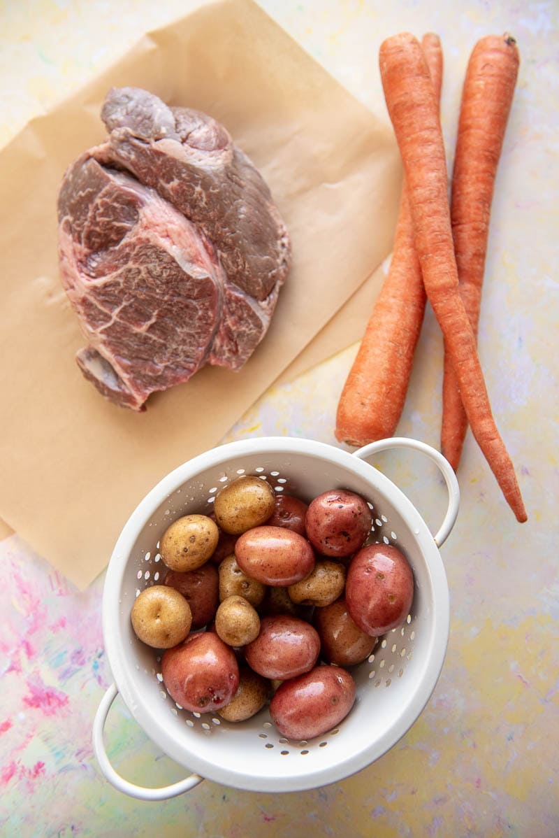 chuck roast, carrots and potatoes raw on cutting board