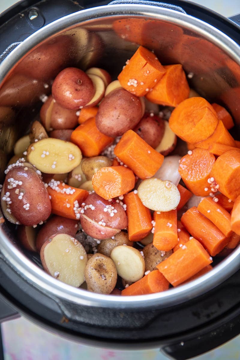 potatoes and carrots on top of beef in instant pot ready to cook