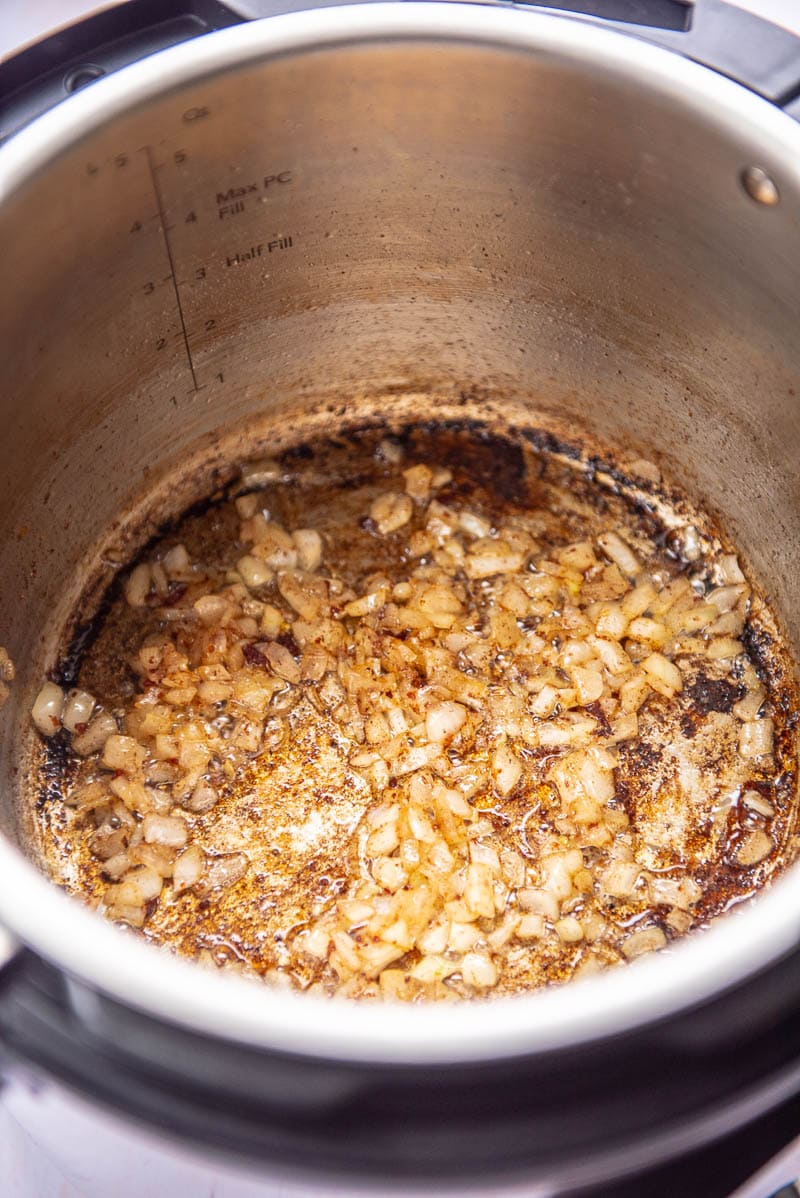 instant pot with cooked onions in bacon greast