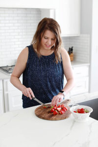 woman in blue tank top slicing strawberries