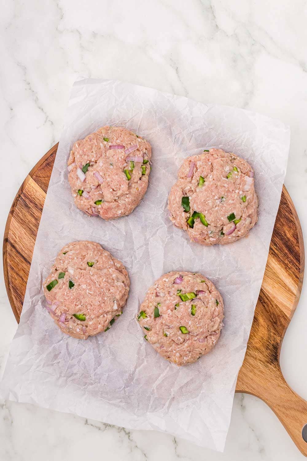 Raw ground turkey patties mixed with red onions on parchment paper, ready for cooking