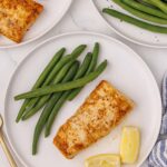 Air fryer mahi mahi served on plate with green beans and slices of lemon