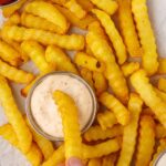 Close up of french fries being dipped in ranch sauce and ketchup