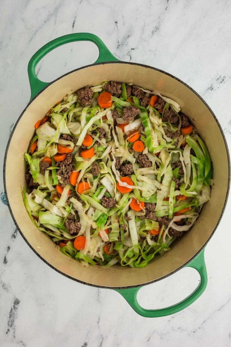 shredded cabbage, carrots and ground beef in dutch oven