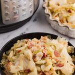 cabbage with bacon in a black bowl in front of Instant Pot