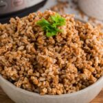 serving bowl in front of instant pot filled with farro