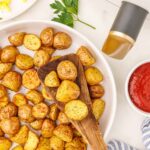 white bowl of air fried potatoes next to white air fryer