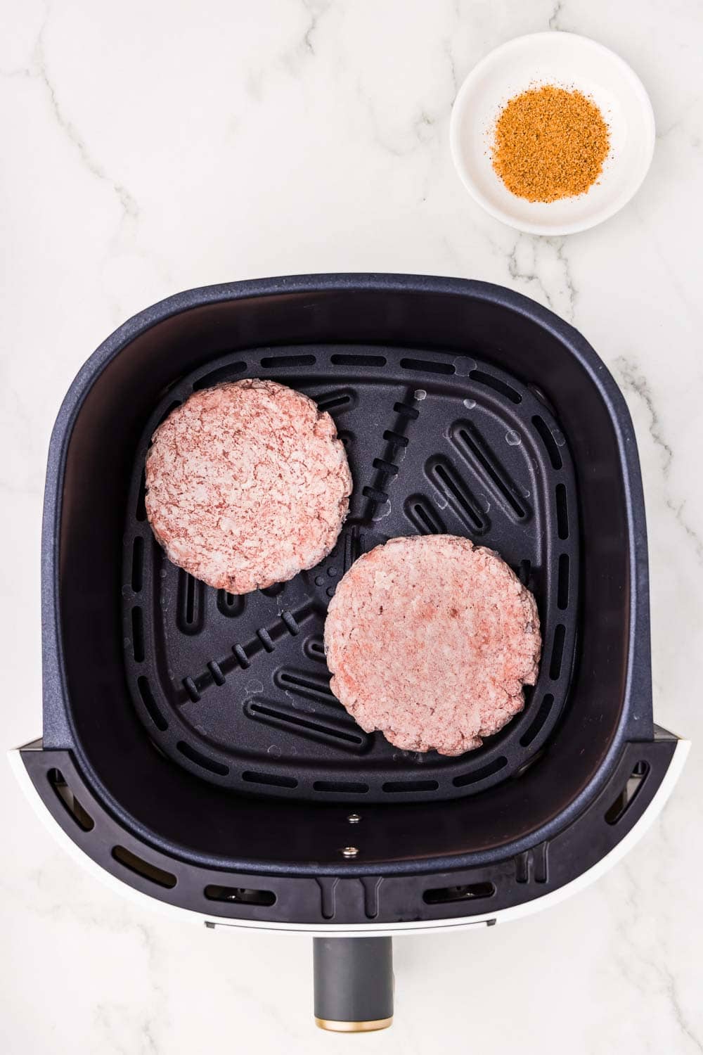 2 uncooked burger patties in air fryer